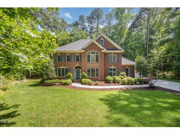 Charming two-story brick home with a manicured lawn and lush landscaping at 8840 Woodyhill Rd, Raleigh, NC 27613