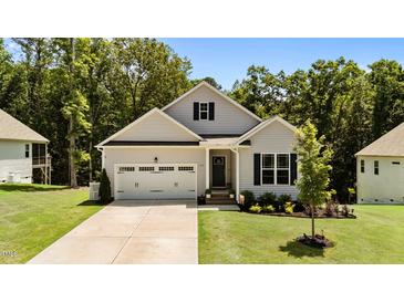 Charming single-Gathering home featuring a two-car garage, well-manicured lawn and lush landscaping at 159 Clear Water Rd, Louisburg, NC 27549