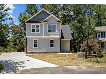 Charming two-story home with gray siding, dark roof, and a concrete driveway surrounded by lush greenery at 5601 Preston Pl, Raleigh, NC 27604
