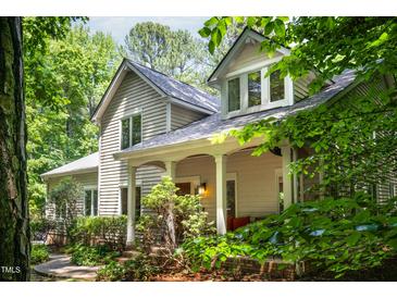 Charming home exterior with classic architectural details, covered porch, and lush landscaping in a wooded setting at 574 Chatham Dr, Chapel Hill, NC 27516