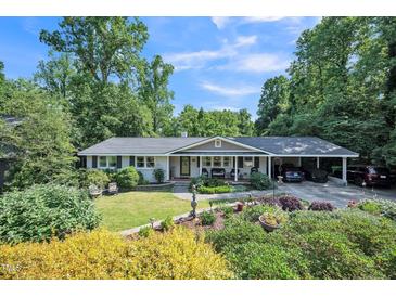 Charming single-story home with a welcoming front porch, lush landscaping, and convenient carport at 582 Wimbleton Dr, Raleigh, NC 27609