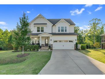 Charming two-story home with a well-manicured lawn and a spacious two car garage and inviting front porch at 6404 Fauvette Lane Ln, Holly Springs, NC 27540