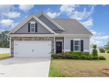 Charming one-story home featuring stone accents, attached garage, and a well-maintained lawn with flower beds at 72 Ina Rose Ln, Four Oaks, NC 27524