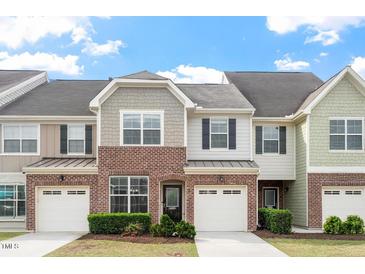 Charming townhome with brick facade, one-car garage, and manicured front yard at 9327 Falkwood Rd, Raleigh, NC 27617