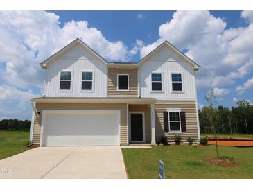 Charming two-story home with a white garage, neutral siding, and a well-manicured lawn at 935 Bombardier Ln, Spring Hope, NC 27882