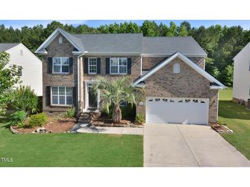 Charming brick two-story home with a two-car garage, manicured lawn, and mature landscaping at 1056 Evening Shade Ave, Rolesville, NC 27571