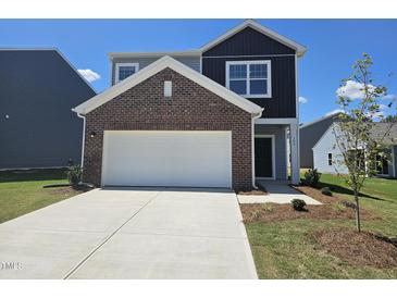 Charming two-story home with a two-car garage and brick accents under a clear blue sky at 109 Gabriel Ct, Wilson's Mills, NC 27520