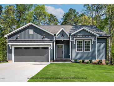 Charming single-story home with gray siding, a two-car garage, and a well-manicured lawn at 154 Buckaroo Dr, Louisburg, NC 27549