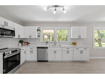 Bright kitchen features white cabinets, stainless steel appliances, light countertops, and a view of the backyard at 2003 Broadway Rd, Sanford, NC 27332