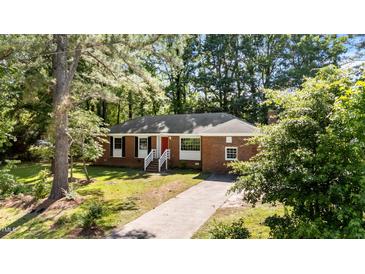 Charming single story brick home featuring a bright red door and mature trees at 208 Essex Rd, Nashville, NC 27856