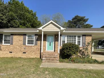 Charming brick home featuring a welcoming turquoise front door and well-maintained landscaping at 305 Briarcliff Dr, Dunn, NC 28334
