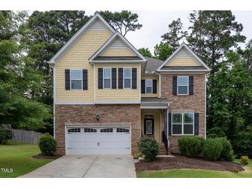 Charming two-story home with stone and yellow shingle exterior and well-manicured lawn at 317 Springhurst Ln, Cary, NC 27511