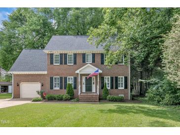 Traditional two-story brick home featuring black shutters, attached garage, and manicured front yard at 418 Old Scarborough Ln, Garner, NC 27529