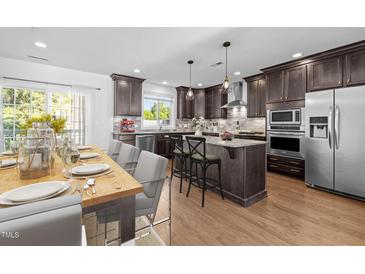 Stylish kitchen features an island, stainless steel appliances, wood floors and a dining area at 531 N Person St # 205, Raleigh, NC 27604