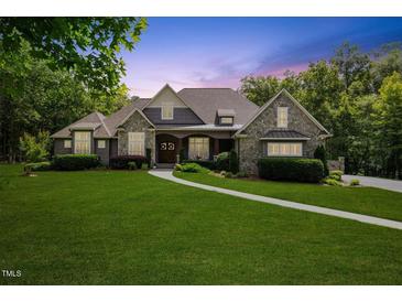 Charming two-story home with stone accents, lush lawn, and professionally landscaped yard at 6500 Bass Mountain Rd, Snow Camp, NC 27349