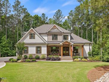Charming two-story home featuring manicured landscaping and a welcoming front porch with rustic wood columns at 67 Spring Hollow Ct, Pittsboro, NC 27312