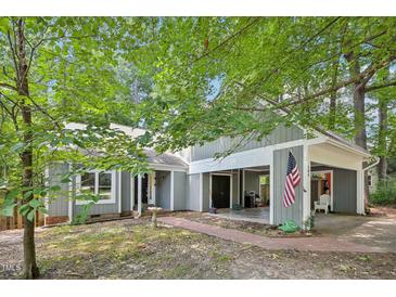 Gray two-story home featuring mature trees, covered parking, and an American flag near the entrance at 103 Lakeway Ct, Cary, NC 27511