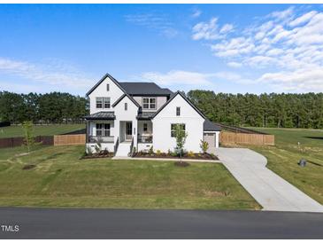 Stunning two-story home featuring a black roof, white brick, manicured lawn and a concrete driveway at 105 Scotland Dr, Youngsville, NC 27596