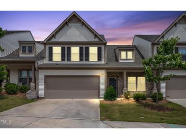 Two-story townhouse showcasing a manicured lawn, two car garage and exterior brick accent at 107 Explorer Dr, Morrisville, NC 27560