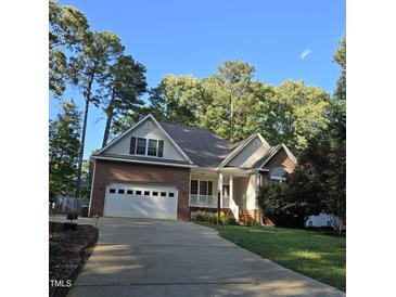 Charming brick and vinyl home with attached garage and well-manicured lawn surrounded by mature trees at 119 Comanche Dr, Louisburg, NC 27549