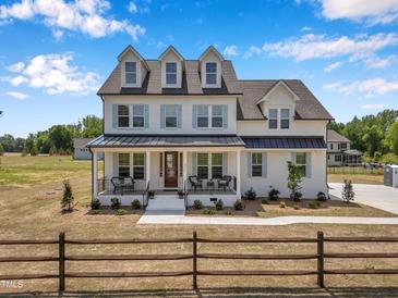 Charming two-story home with black roof, white siding, and a cozy front porch in a serene country setting at 2371 Old Us 421, Lillington, NC 27546