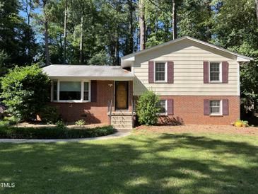 Charming two-story home with red brick and light yellow siding, complemented by lush greenery and a well-manicured lawn at 3205 Broyhill Cir, Raleigh, NC 27604