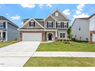 Charming two-story home featuring a stone facade, two-car garage, and a well-manicured lawn at 33 Black Walnut Dr # 185, Garner, NC 27529