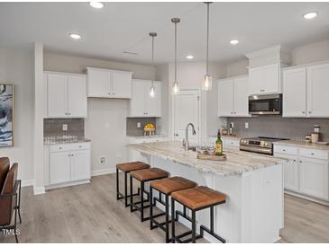 A bright kitchen with an island, granite countertops, pendant lighting, and stainless steel appliances at 433 Old Fashioned Way, Lillington, NC 27546