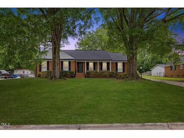 Charming brick home featuring a lush green lawn and mature trees at 5110 Old Well St, Durham, NC 27704