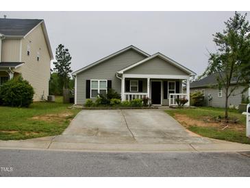 Charming single-story home with a concrete driveway and cozy front porch in a residential neighborhood at 764 Grove Creek Ln, Raleigh, NC 27610