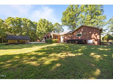 Sprawling backyard showing the brick home and detached garage on a sunny day at 1973 Elon Ossipee Rd, Elon, NC 27244