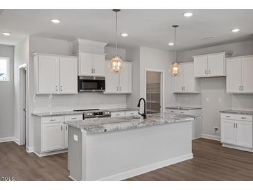 New kitchen features white cabinets, granite countertops, stainless appliances and modern pendant lighting at 224 Wild Turkey Way, Lillington, NC 27546