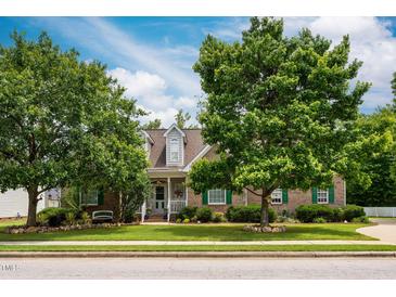 Charming brick home with a well-manicured lawn and mature trees providing shade and curb appeal at 229 Hocutt Farm Dr Dr, Clayton, NC 27527