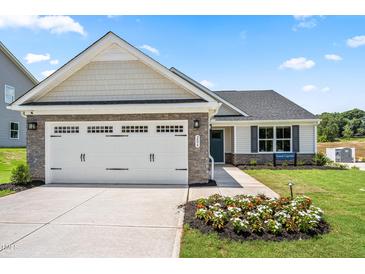 Charming new construction home featuring a two-car garage, stone accents, and beautifully landscaped front yard at 30 Elmwood Ave, Sanford, NC 27330