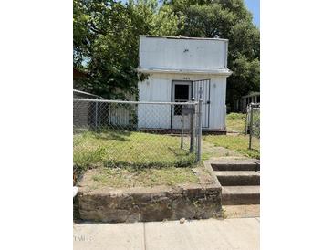 Exterior front view of small, white one-story home with number 1403 above door and chained fence at 1403 S Roxboro Street, Durham, NC 27703
