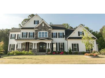 Charming two-story home with stone accents, black shutters, manicured lawn, and a welcoming front porch at 1475 Sierra Glen Cir, Apex, NC 27502