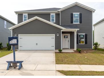 Two-story home featuring a white garage door, grey siding, black shutters, and a well-maintained lawn at 2250 Cherry Creek Rd, Haw River, NC 27258