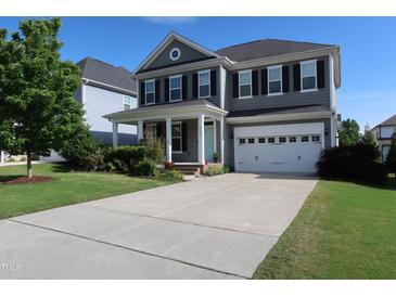 Charming two-story home with a manicured lawn, two car garage, and a welcoming light blue front door at 2309 Redbridge Ln, Apex, NC 27502
