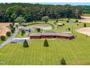 Expansive estate featuring a charming brick home, serene pond, and lush landscaping from an elevated perspective at 3187 Wilsons Mills Rd, Smithfield, NC 27577