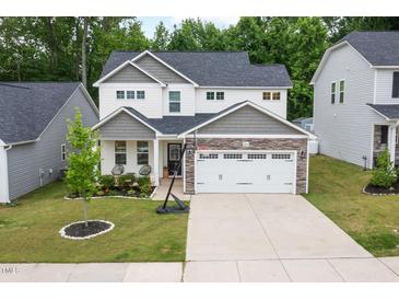 Charming two-story home featuring a manicured lawn, stone accents, and a spacious two-car garage at 389 Whetstone Dr, Angier, NC 27501