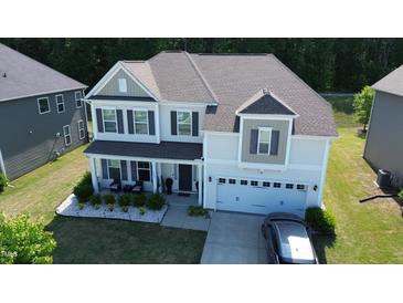 Two story home with attached garage, neutral siding, front porch, dark shutters and lush landscaping at 4907 Sleepy Falls, Knightdale, NC 27545