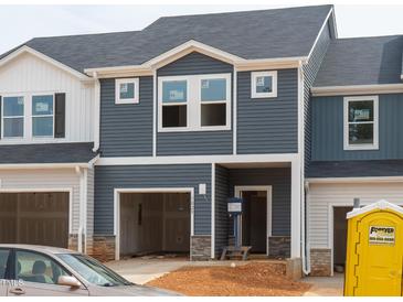 Modern townhome featuring blue siding, stone accents, open garage and covered front entry at 1029 Winding Spring Dr, Mebane, NC 27302