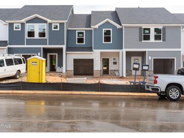 New townhomes with attached garages are under construction, featuring mixed siding and dark grey roofs at 1031 Winding Spring Dr, Mebane, NC 27302