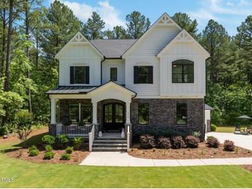Stunning two-story home with a combination of stone and white wood and a welcoming front porch at 1338 The Parks Dr, Pittsboro, NC 27312