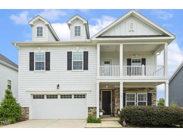 Charming two-story home featuring a welcoming front porch, a two car garage, and manicured landscaping at 145 Cassada Ct, Holly Springs, NC 27540