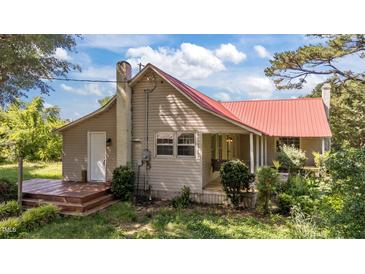 Charming home featuring a durable red metal roof, deck and well-maintained lawn at 1908 Rocky Cross Rd, Zebulon, NC 27597