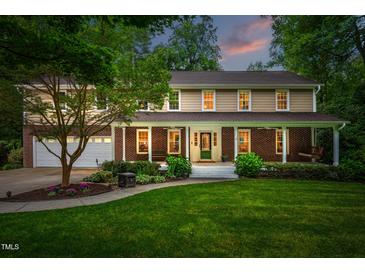 Charming two-story home featuring a welcoming front porch, manicured lawn, and beautiful landscaping at 8608 Valley Brook Dr, Raleigh, NC 27613