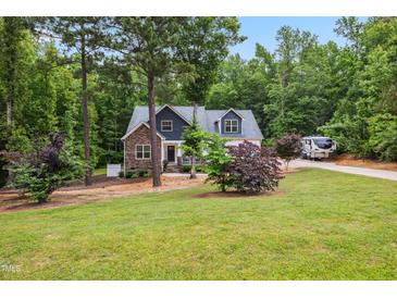 Charming home exterior with stone accents, lush landscaping, and a spacious front yard at 100 Lexington Ave, Zebulon, NC 27597