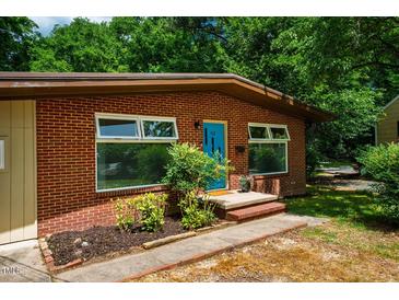Charming brick home exterior with a bright blue front door and manicured landscaping at 112 Noble St, Chapel Hill, NC 27516