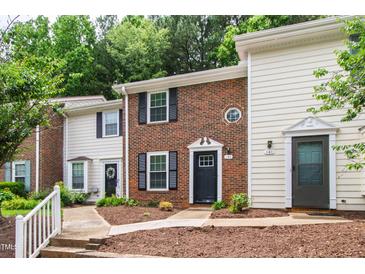 Charming townhome with brick facade, black shutters, and meticulously landscaped front yard at 129 Assembly Ct, Cary, NC 27511